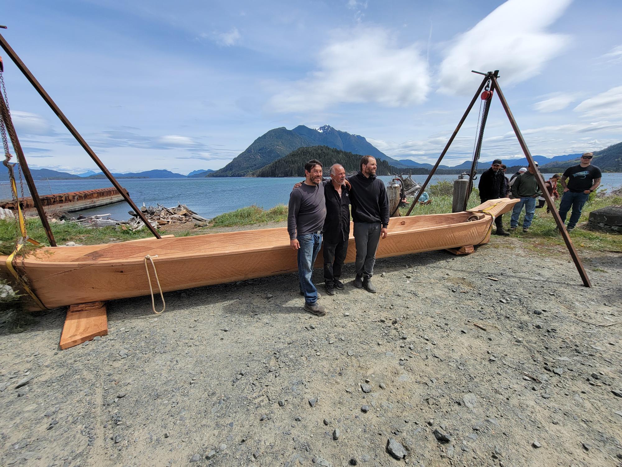 carvers stand in front of canoe